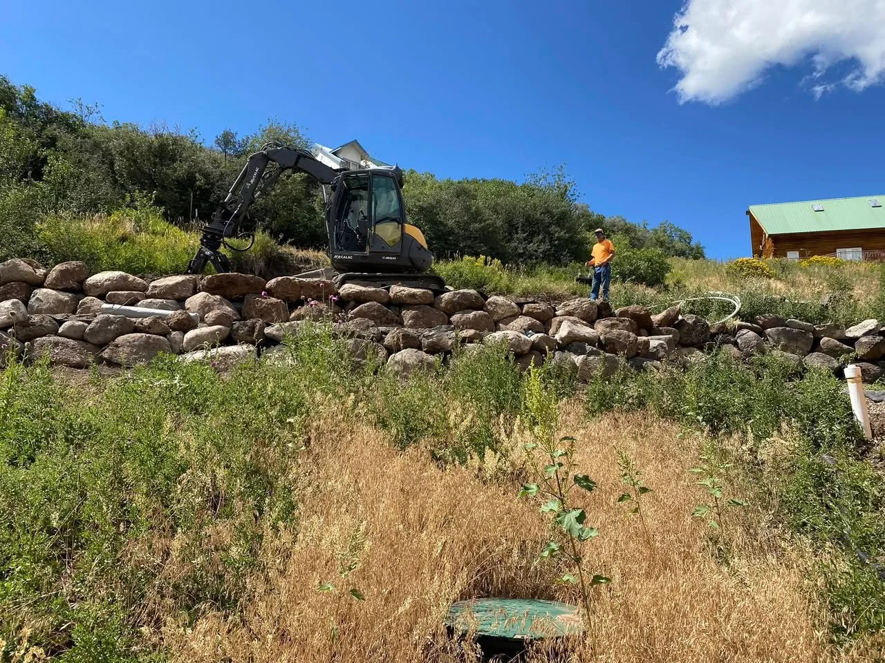Excavator working above a wall of large boulders