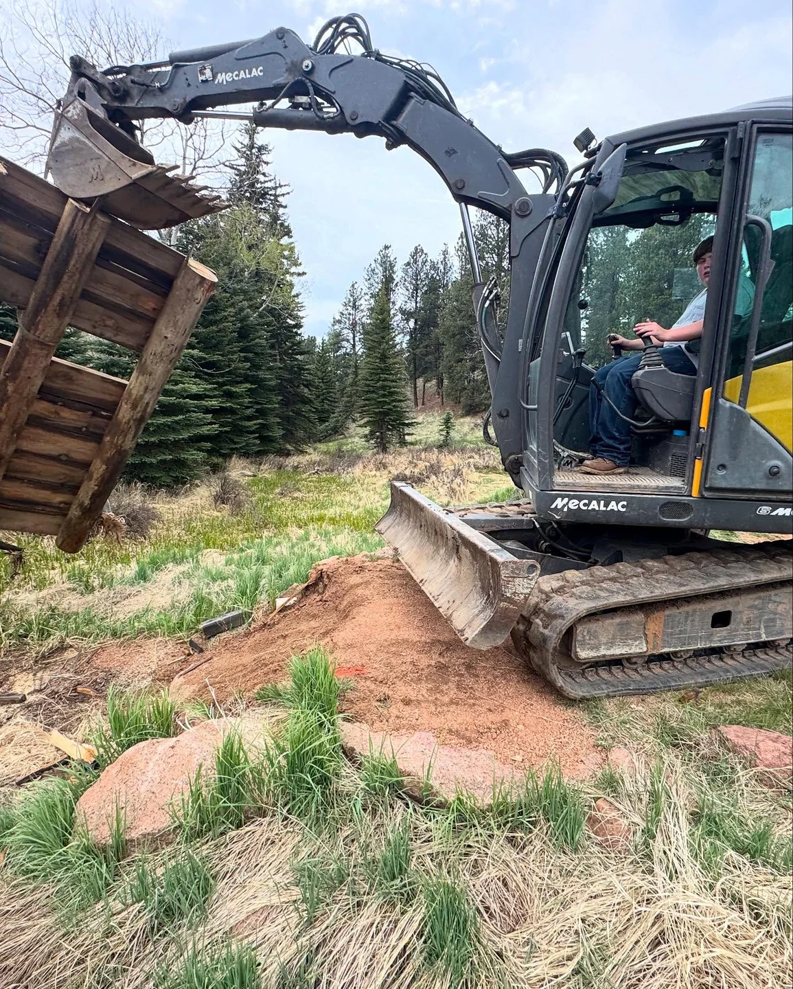 Excavator and attachment on a wooded dirt access route