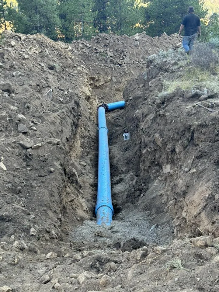 Blue vertical pipe exposed in an excavated trench